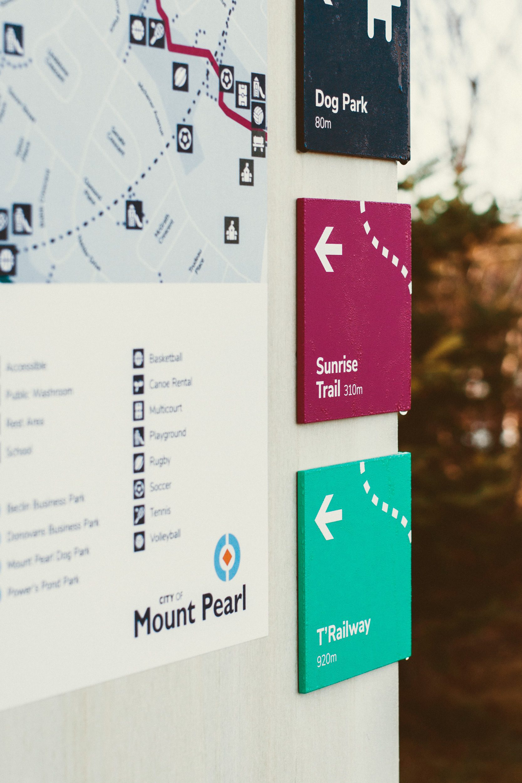A closeup of a Mount Pearl trail information kiosk showing arrows to two trail systems